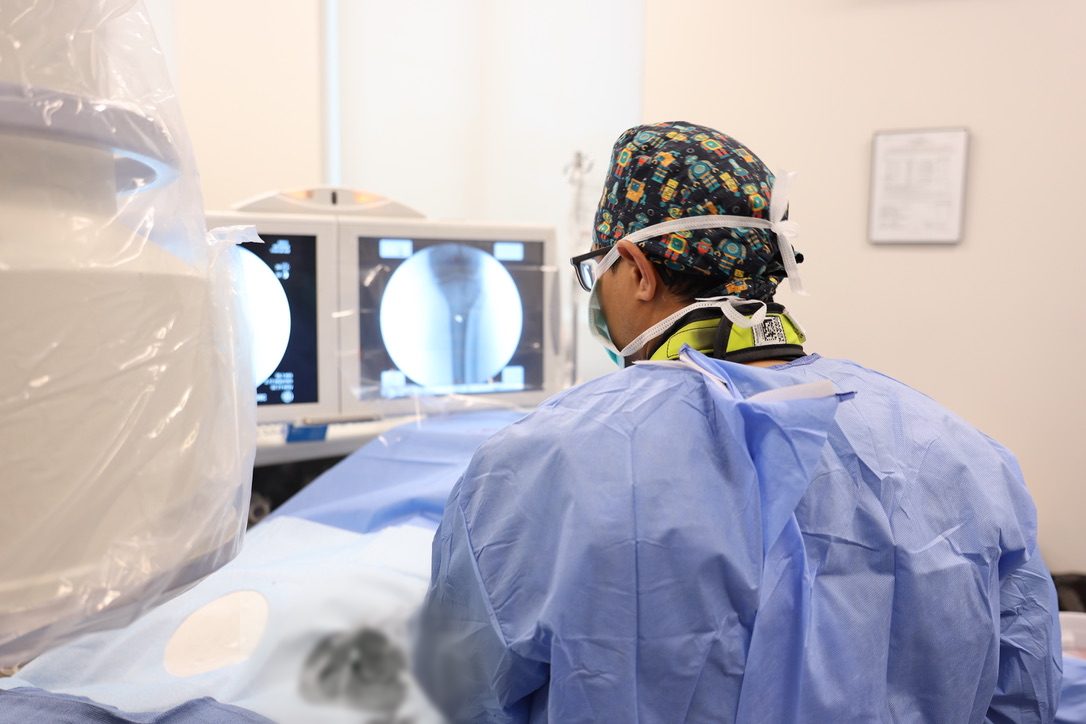 Arthur S. Joseph, D.O., M.P.H. performing a genicular artery embolization at ARV Centers in San Antonio, watching the live angiogram of the knee on the imaging screen