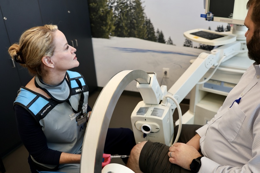 Dr. Lisa Persyn performing an image-guided knee injection while the patient watches the live screen at ARV Centers